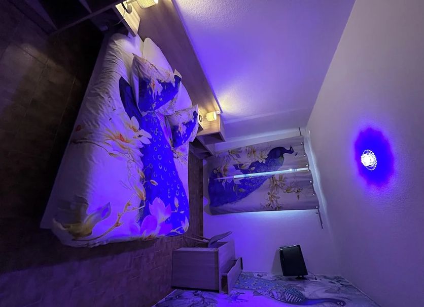Horus Hôtel & Spa in Fréjus room with purple lighting, patterned bed, and sofa