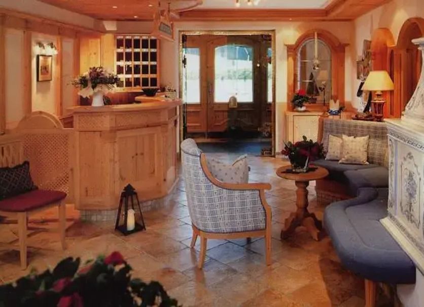 Hotel Garni Alpenland in Altenmarkt im Pongau: cozy lobby with seating, reception desk and ornate tiled stove