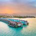 Hard Rock Hotel Maldives in Malé with overwater villas above turquoise water at sunset