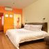 Yanjiang East Garden Inn Guangzhou room with bed, desk, chair, and orange accent wall