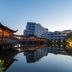 Xiang Ming Luxury Airport Hotel in Huangshan reflected in a calm pond beside a lit pavilion and tower