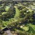 Aerial view of Matador Motor Inn in Coffs Harbour beside a lush golf course with ponds and fairways.