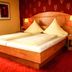 Stadthotel Augsburg guest room with double bed, bedside lamps and red patterned carpet in Augsburg