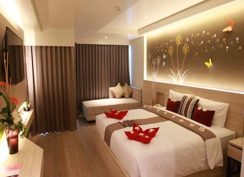 Levana Pattaya Hotel guest room with twin beds, daybed, wall art, and curtains in Pattaya