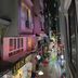 Funny Guesthouse in Ho Chi Minh City on a narrow, busy street at night with bright storefront lights