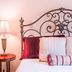 Brick Street Inn Zionsville guest room with wrought-iron headboard, bedside lamp and adjoining bedroom view