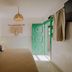 Hotel Cielo y Selva room with bed, woven pendant light and open green door in San Cristóbal de las Casas