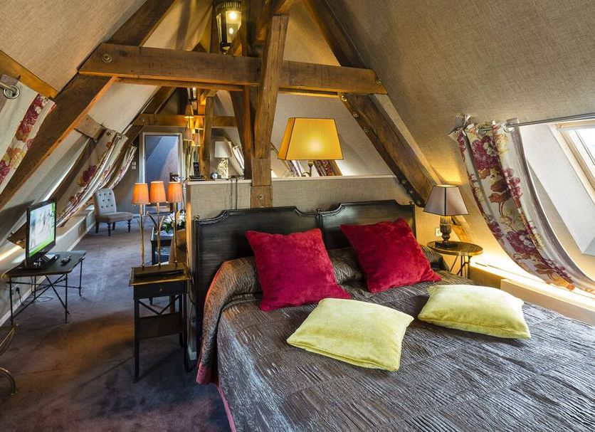 Chateau De Fere in Fère-en-Tardenois: attic suite with exposed beams, double bed, and skylight