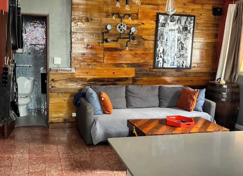 Coqui del Mar Guesthouse in San Juan with a cozy lounge, gray sofa, wood walls, and small table