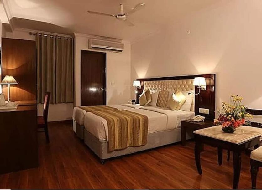 Hotel Impress By Rmr Hotels in New Delhi features a guest room with king bed, desk, and warm lighting