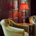 Penmaenuchaf Hotel in Dolgellau lounge with two olive armchairs, red lamp and dark wood paneling