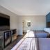 Motel 6 Burlington NC room with two beds, blue accent wall, TV cabinet and natural light in Burlington