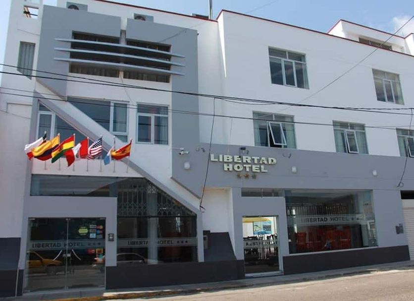 Libertad Hotel in Trujillo, exterior view of the white facade with entrance and flags