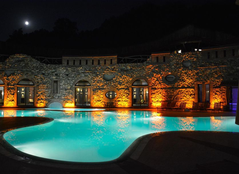 Gazelle Resort & Spa in Karacasu with lit outdoor pool beside a stone hotel facade at night