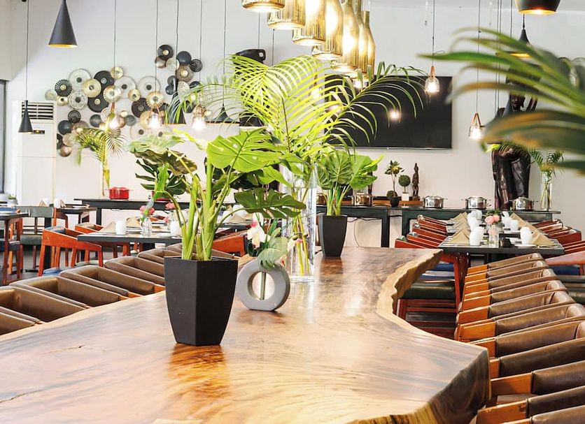 Riviera Royal Hotel in Conakry dining area with long wooden table, potted plants and hanging lights