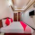 Hotel Ik London Residency Hyderabad bedroom with double bed, wall-mounted TV and wood closet