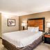 Quality Inn Pensacola North guest room with king bed, bedside lamps, and patterned chair in Pensacola