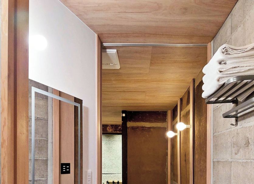 Machiya Hotel Yanagi in Kyoto corridor with bench, towels, and wood-paneled ceiling