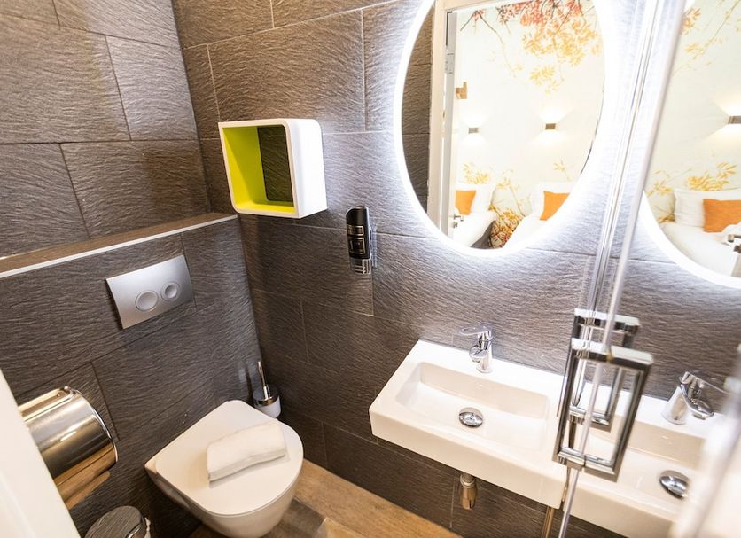 Hotel Pagi Amsterdam bathroom with toilet, twin sinks and illuminated oval mirrors