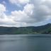 Minshuku Unagi Kohan in Ibusuki with a calm lake and green mountains under cloudy sky
