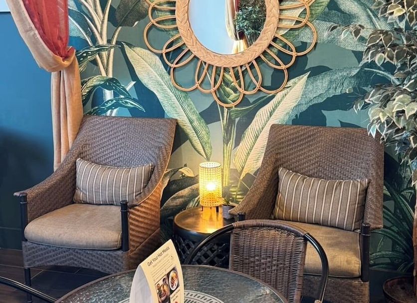 Greentree Inn & Suites Alhambra lounge with wicker chairs, side table, lamp and tropical mural wall