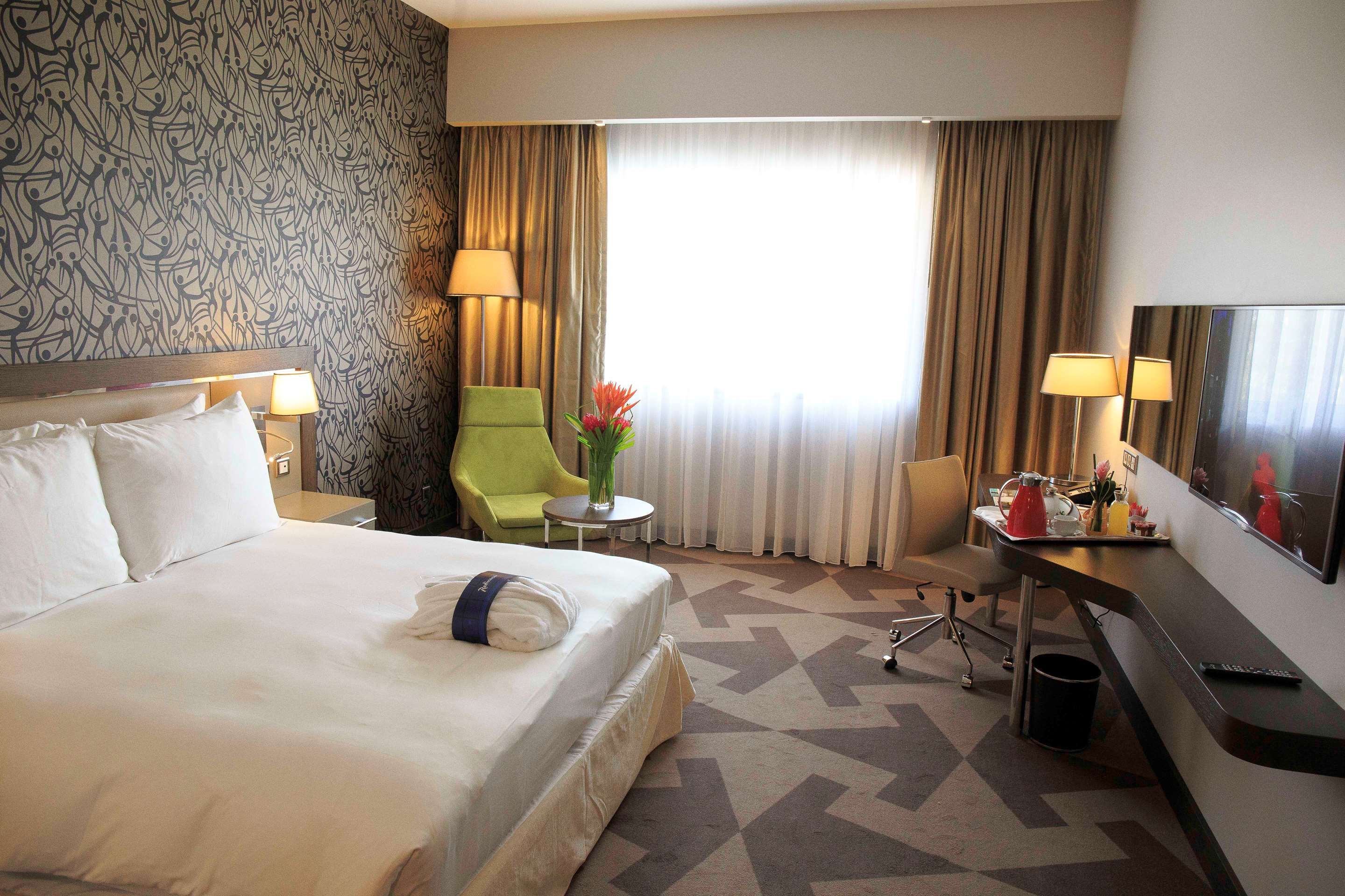 Radisson Blu Hotel, Abidjan Airport guest room with king bed, desk, seating area and large window