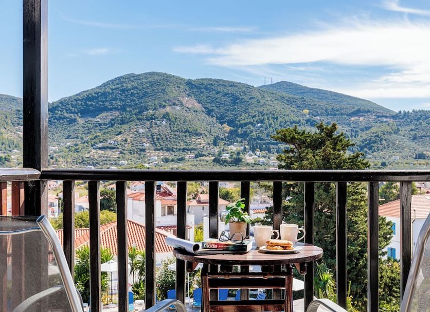 Hotel Dionyssos in Skopelos balcony with table and chairs overlooking mountains and village
