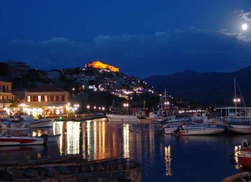 Moonlit harbor view in Míthymna from The Schoolmistress With The Golden Eyes, with boats and reflections