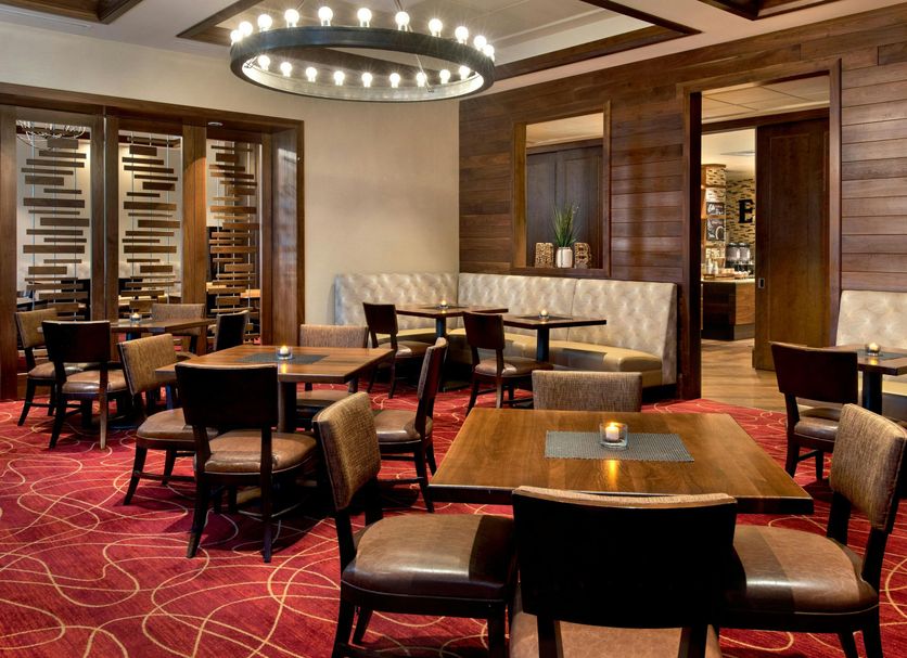 Philadelphia Airport Marriott lounge with wood tables, tufted banquette seating and patterned red carpet in Philadelphia