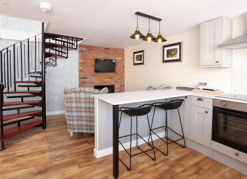 Broom Hall Inn in Alcester: stylish suite with spiral staircase, kitchen island, bar stools and brick feature wall