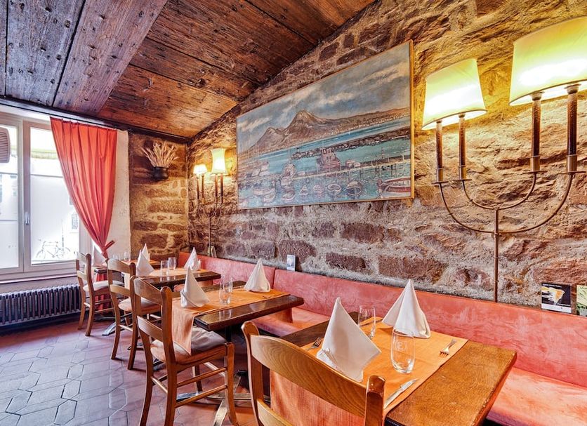 Hotel Restaurant Resslirytti in Basel dining room with stone walls, wood tables, and red banquette seating
