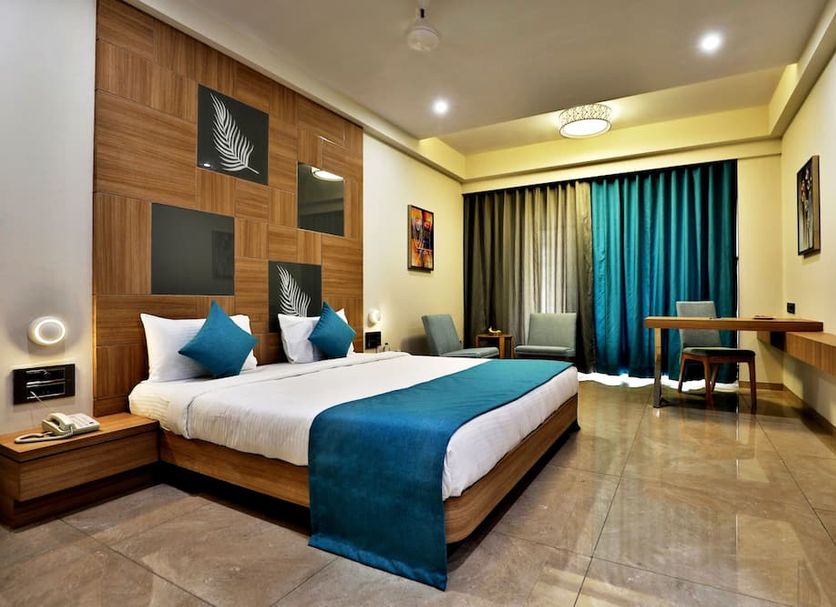 VITS Devbhumi Dwarka guest room with king bed, teal accents, desk, and balcony curtains in Dwārka
