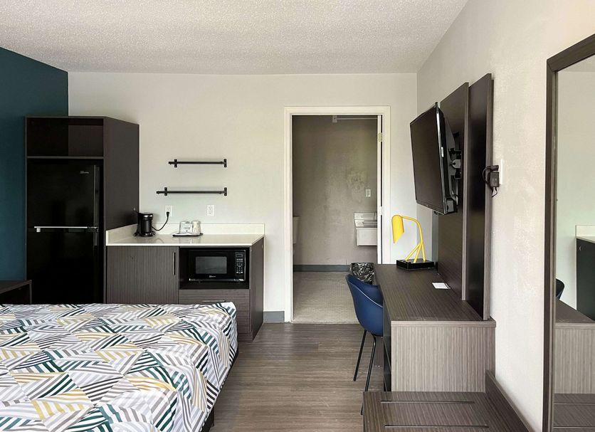 Studio 6 Suites Lafayette guest room with bed, desk, wall-mounted TV and kitchenette area