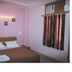 Hotel Landmark Haridwar guest room with double bed, wall light, window AC and curtains