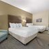 Best Western Brockport Inn & Suites guest room with two queen beds and an armchair in Brockport.