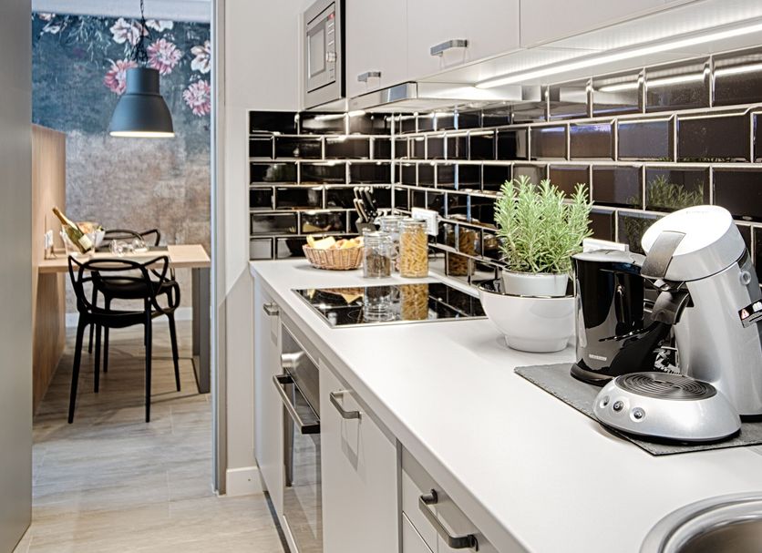 Mloft Apartments München kitchen with white countertops, black tile backsplash, coffee maker and dining nook in Munich