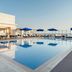 Riviera Rayhaan by Rotana Doha rooftop pool with blue umbrellas and loungers in Doha