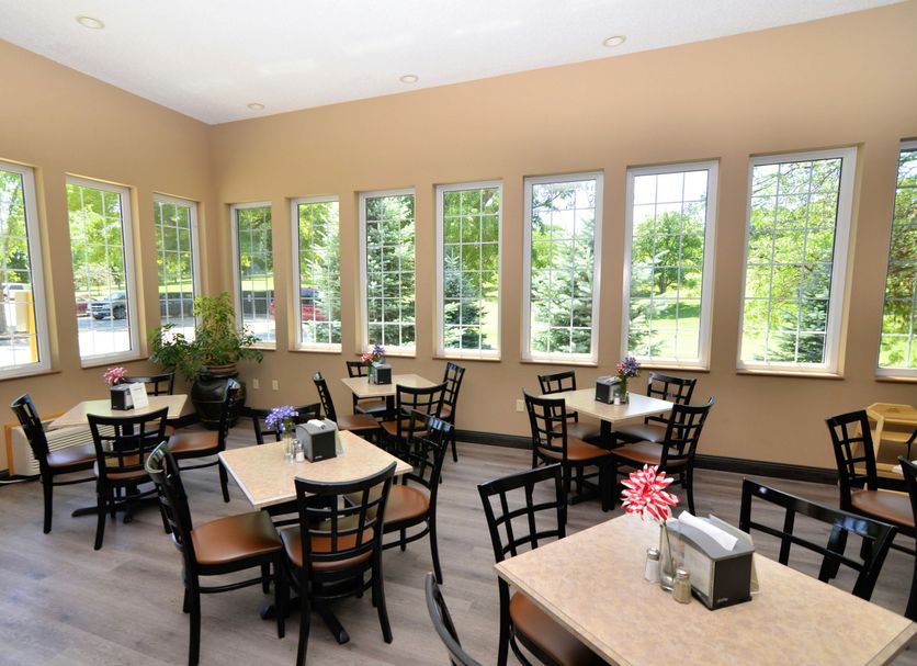 Cobblestone Inn & Suites - Denison breakfast room with tables and chairs, and large windows overlooking trees
