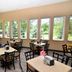 Cobblestone Inn & Suites - Denison breakfast room with tables and chairs, and large windows overlooking trees