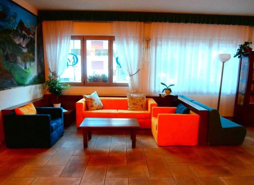 Hotel Orsa Maggiore in Falcade lounge with colorful sofas, coffee table, window and tiled floor