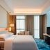 Sheraton Zibo Hotel guest room with king bed, city view windows, TV, and blue carpet in Zibo