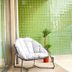 Acta The Avenue in Porto with a cushioned chair beside a glass wall and mosaic green tiles