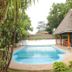Kiriri Residence Hotel in Bujumbura with an outdoor swimming pool and thatched poolside seating