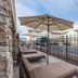 Hampton Inn Colorado Springs-Airport patio with lounge chairs and umbrellas beside a fenced parking lot