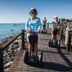 Guests ride Segways along the waterfront at Beach Court Holiday Villas in Airlie Beach, with ocean views.