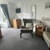 Gwyndra House B&B in St. Austell seating area with armchairs, mirror, dresser and window with curtains