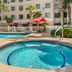Best Western Plus Valdosta Hotel & Suites in Valdosta: outdoor pool and hot tub with palm trees and red umbrellas