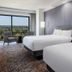 Horseshoe Tunica guest room with two beds, floor-to-ceiling window and chair overlooking trees in Tunica Resorts