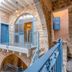 Arabesque Arts & Residency in Akko, stone courtyard with blue shutters, arched balcony, and blue railings