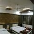 Nice Guest House Mumbai room with two beds, patterned accent wall, ceiling fan, and curtained window
